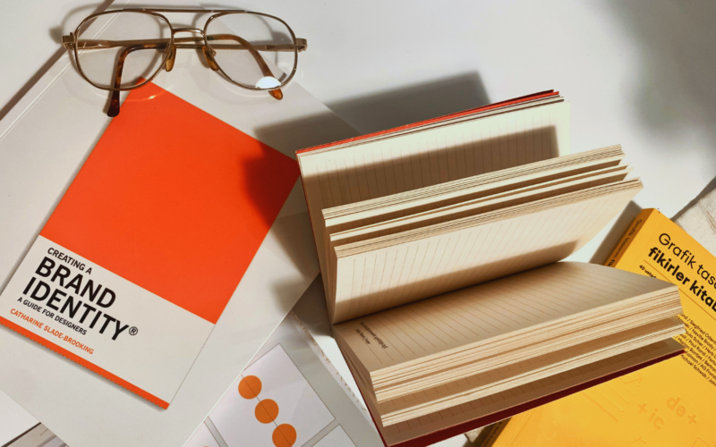 Design books, open notebook, and glasses on desk